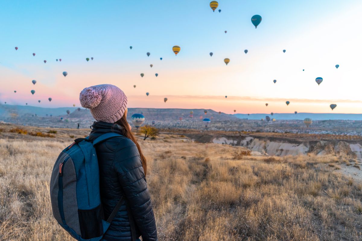 A traveller watching balloons over a landscape