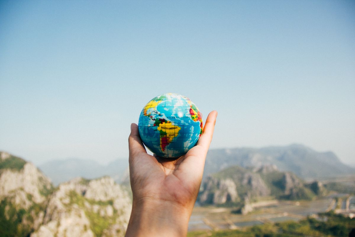 A small globe held against a landscape