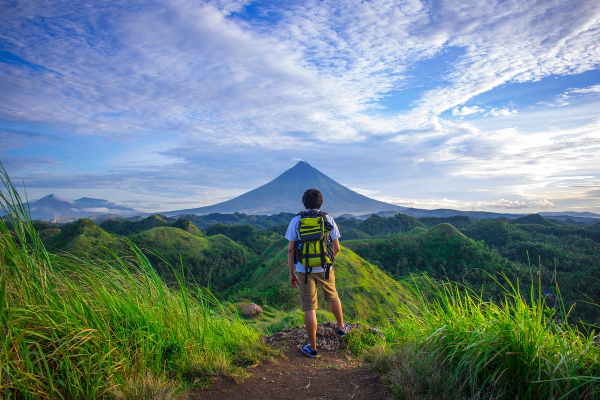 A hiker overlooking a green volcanic landscape